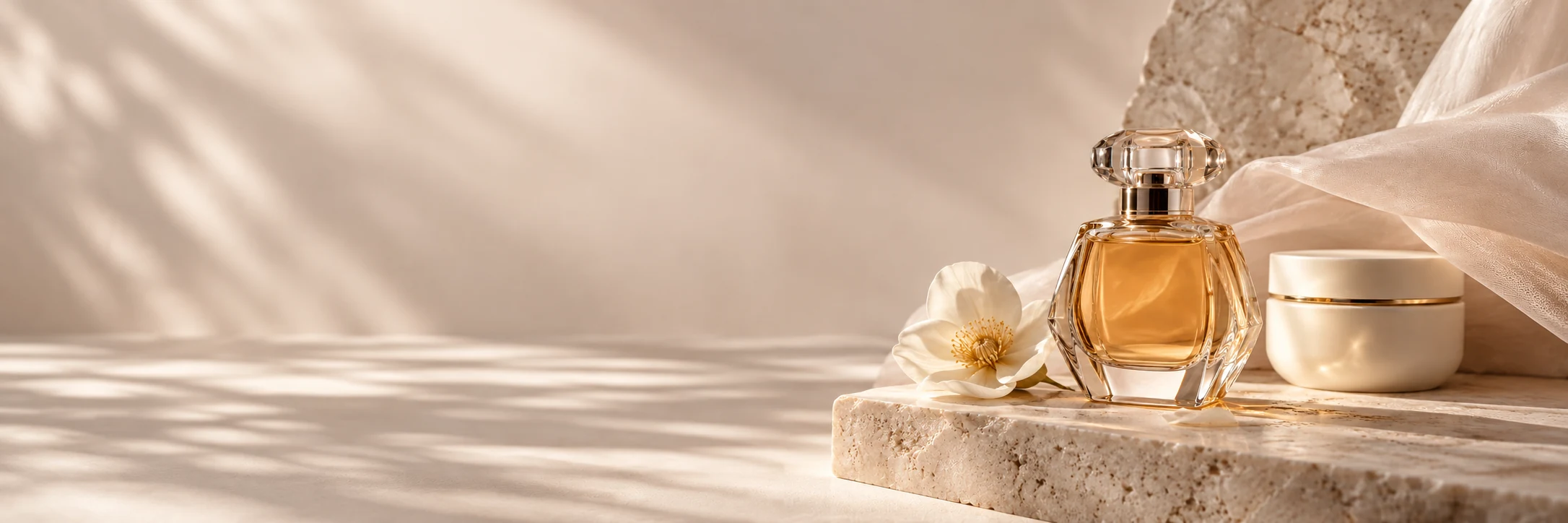 Escena editorial panorámica de perfumes, flores y piedra clara